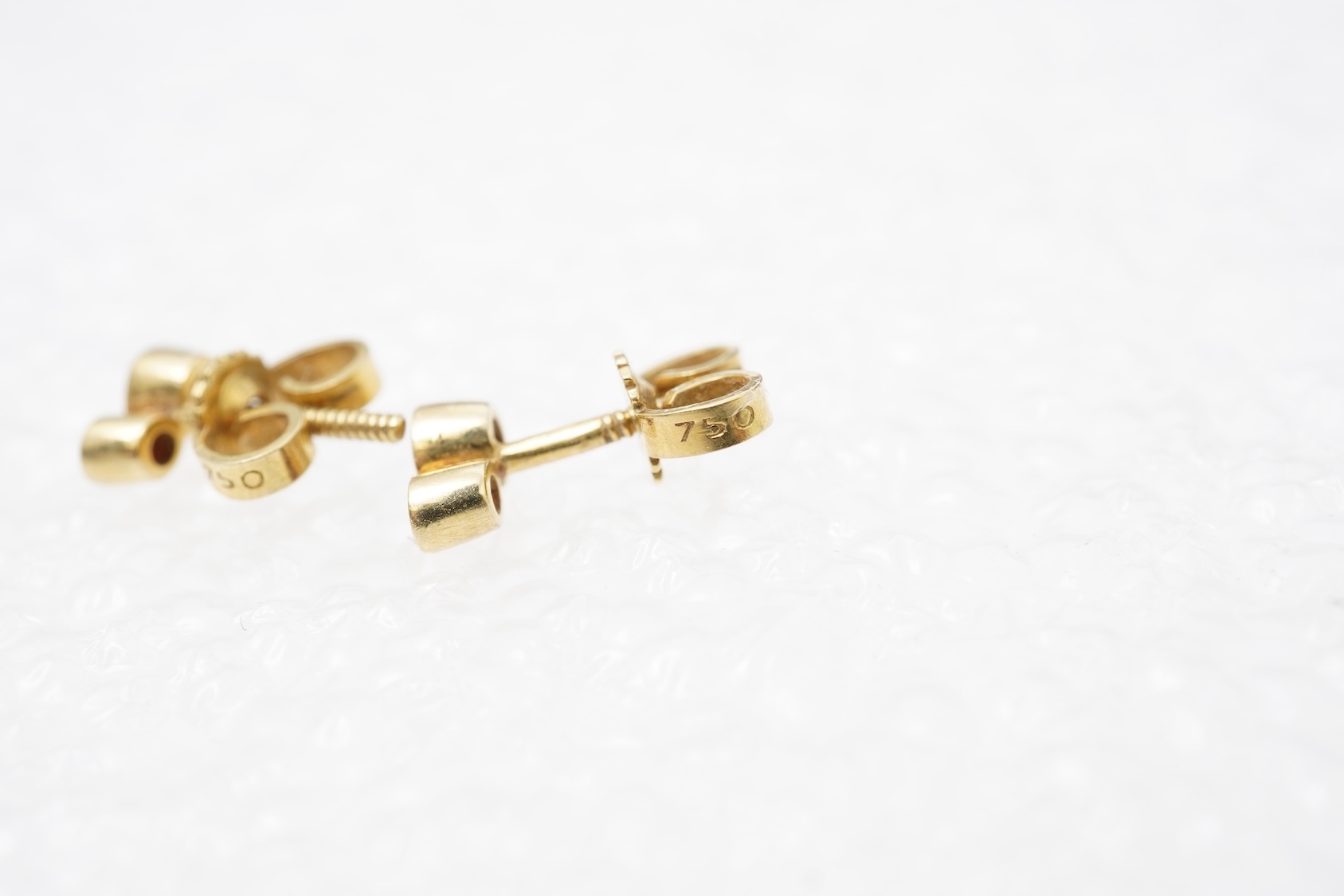 A pair of ruby and diamond stud earrings, set with brilliant-cut diamonds totalling approximately 0.15 carats, surmounted by circular-cut rubies, in gold collet settings, length 0.6cm each, post fittings